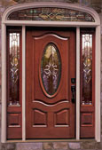 Woodgrain front door with decorative glass oval in the middle and decorative sidelites.