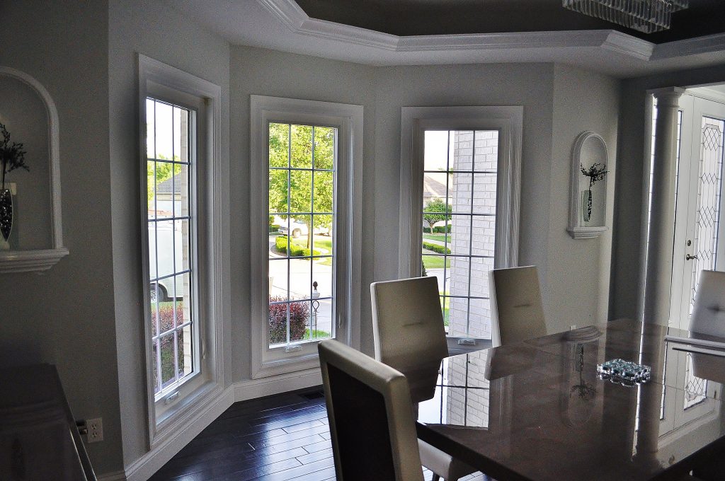 A modern, clean dining room, with three, long windows in the background