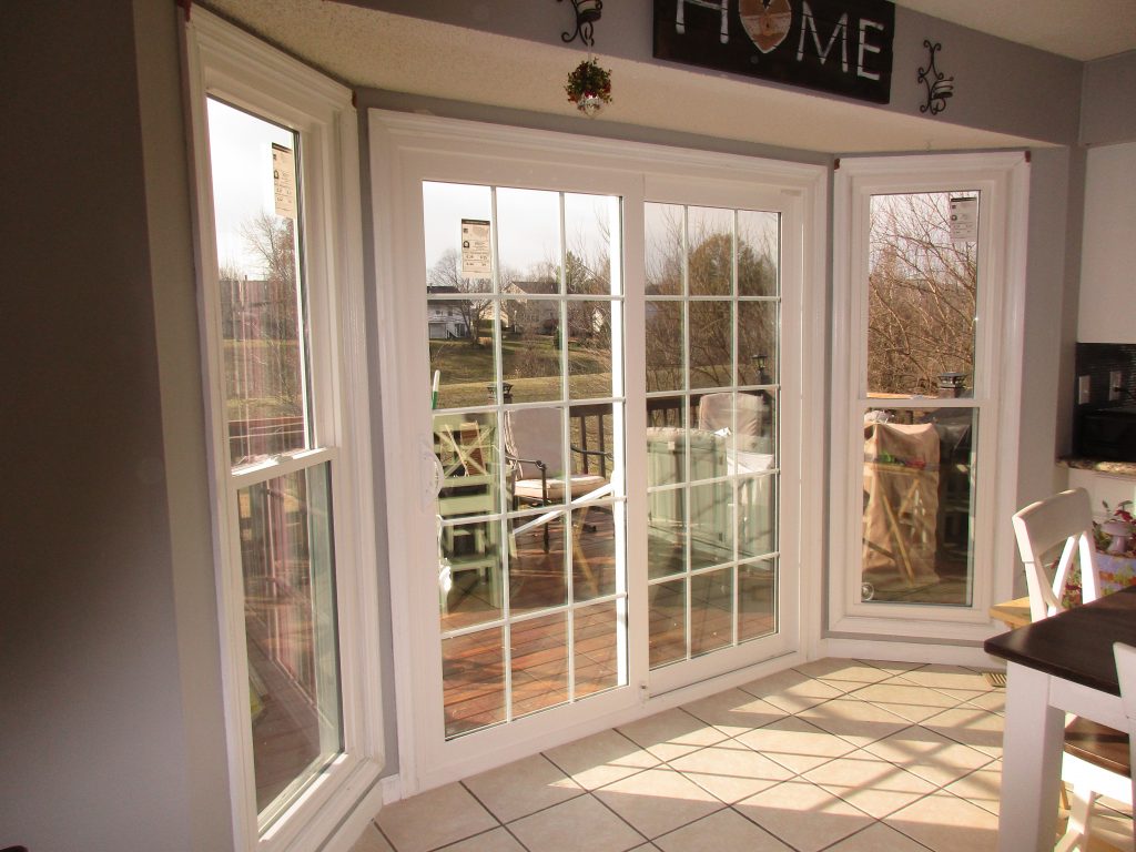 Sliding white patio door with grids and two single-hung windows.