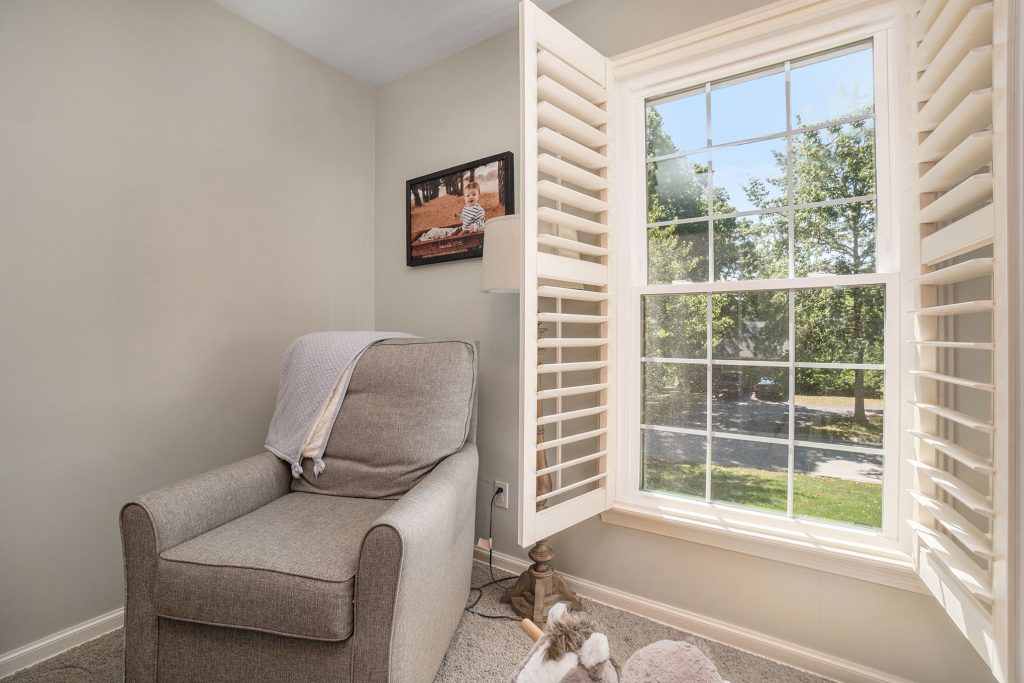 Double-hung windows in bedroom with open shutter blinds.